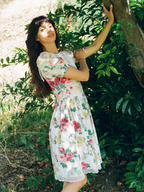 Woman in a floral dress standing among greenery
