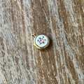 Small embroidered pendant with a pink rose on a wooden surface