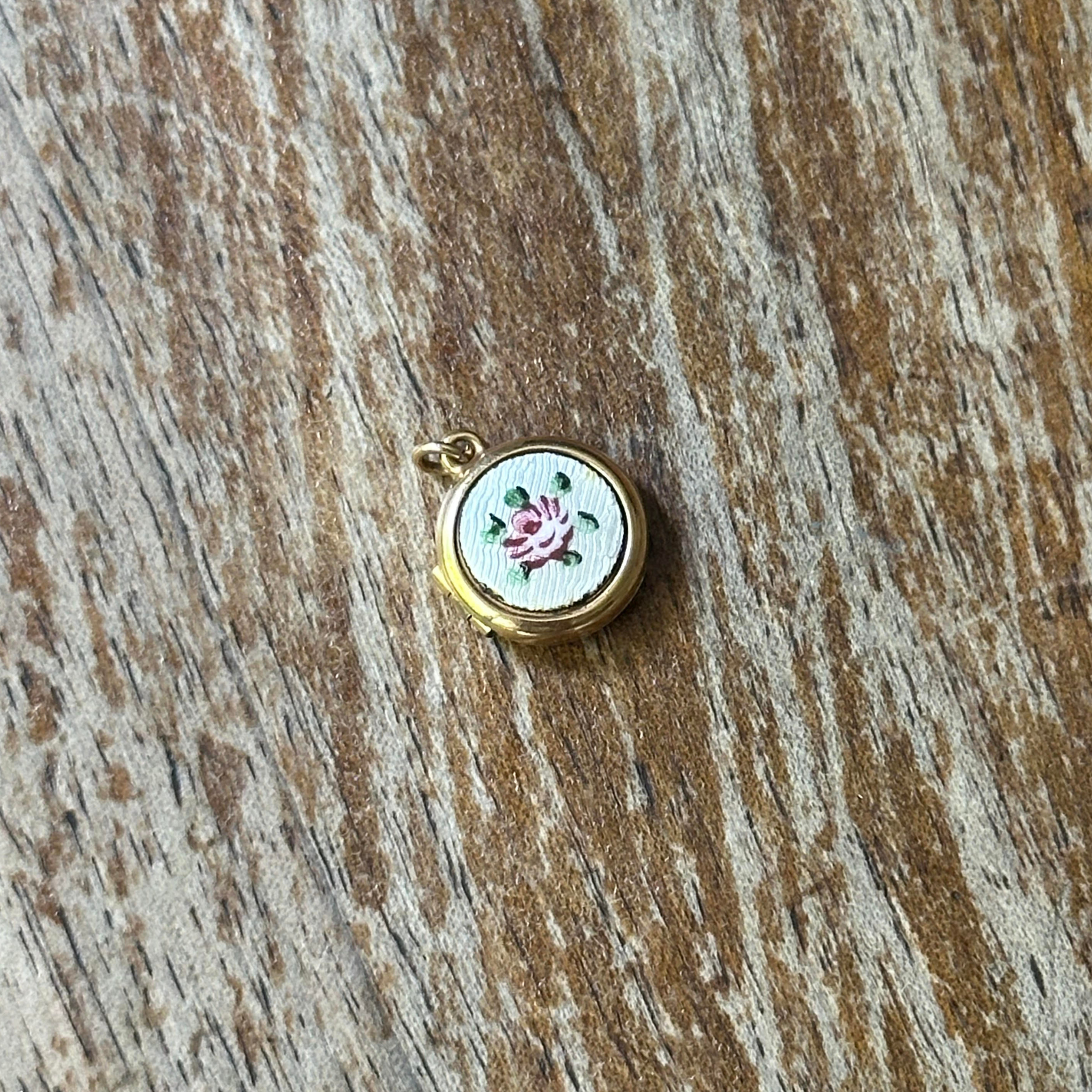 Small embroidered pendant with a pink rose on a wooden surface