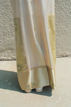Light-colored fabric with floral patterns draped over a surface against a textured wall.