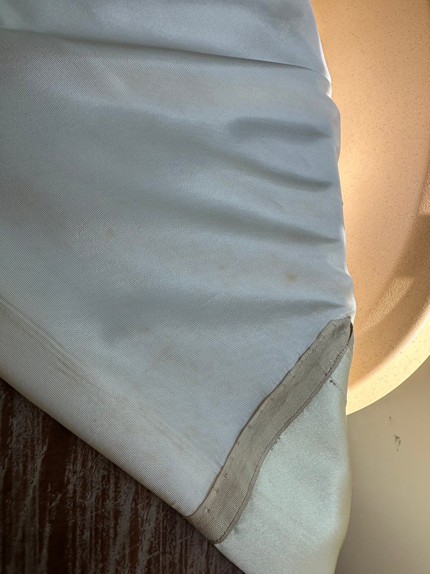 Close-up of a white fabric surface with a wooden texture underneath