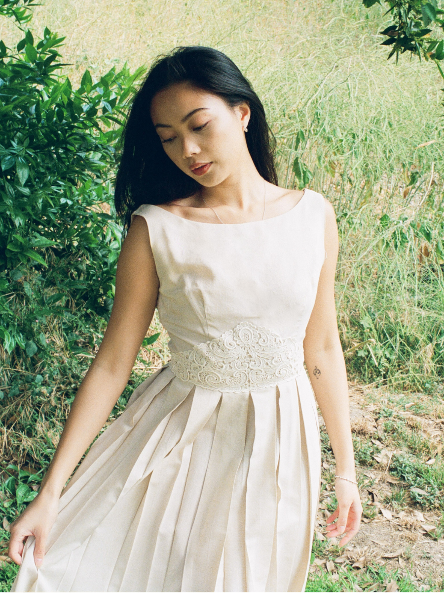 Woman in a white dress standing outdoors with greenery around