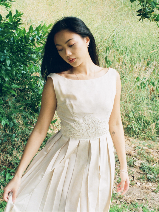 Woman in a white dress standing outdoors with greenery around