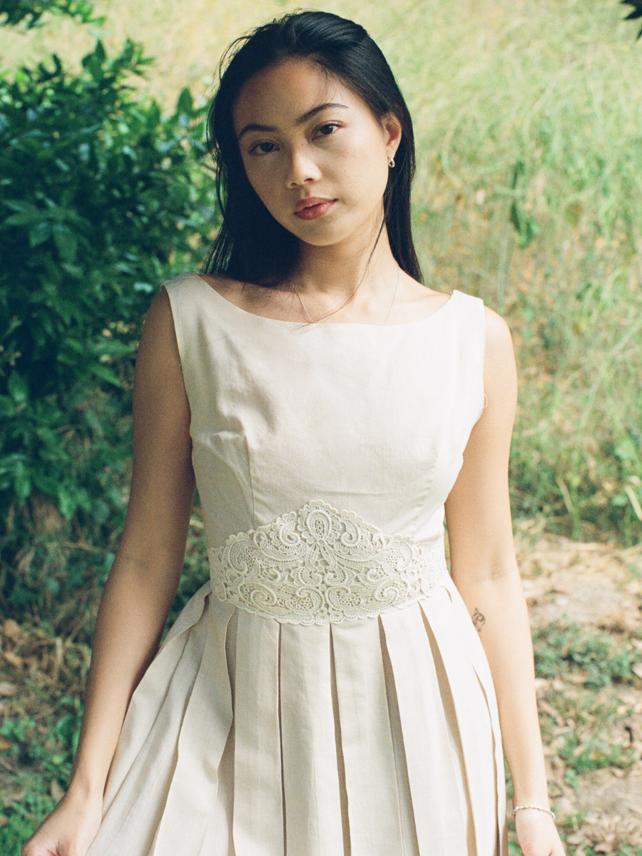 Woman wearing a light-colored dress with lace detail in an outdoor setting