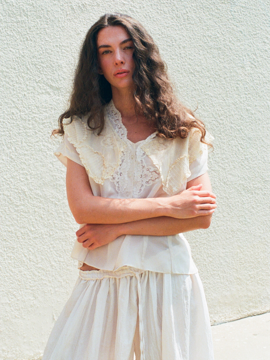Woman wearing a white lace top and skirt against a light background