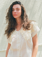 Woman wearing a white lace blouse against a light background