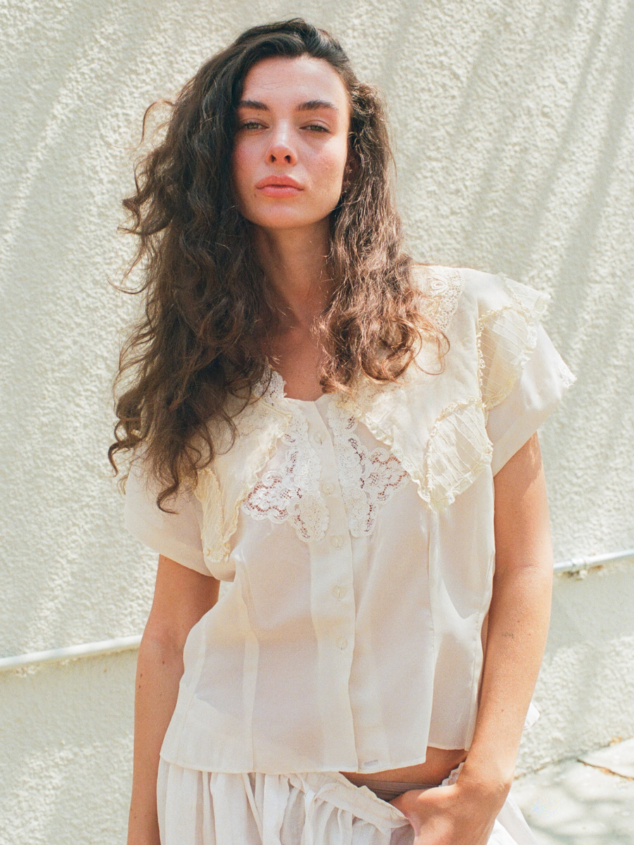 Woman wearing a white lace blouse against a light background