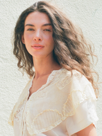 Woman wearing a light-colored lace top against a neutral background