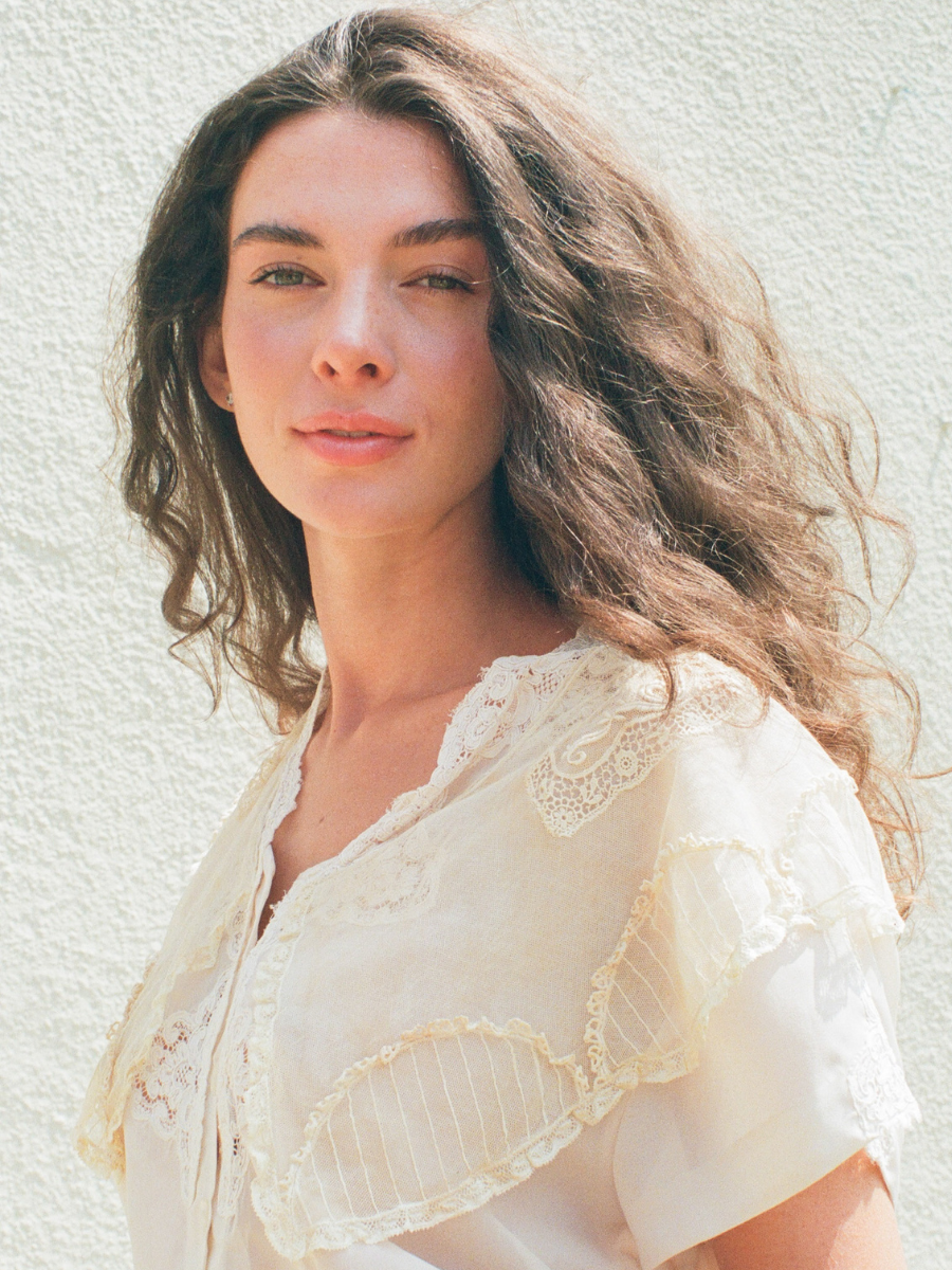 Woman wearing a light-colored lace top against a neutral background