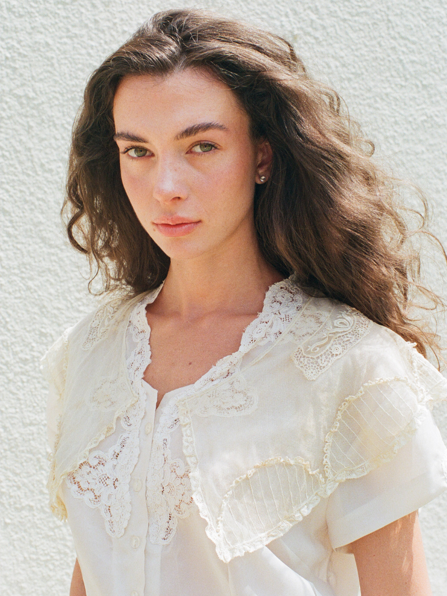 Woman wearing a white lace blouse against a light background