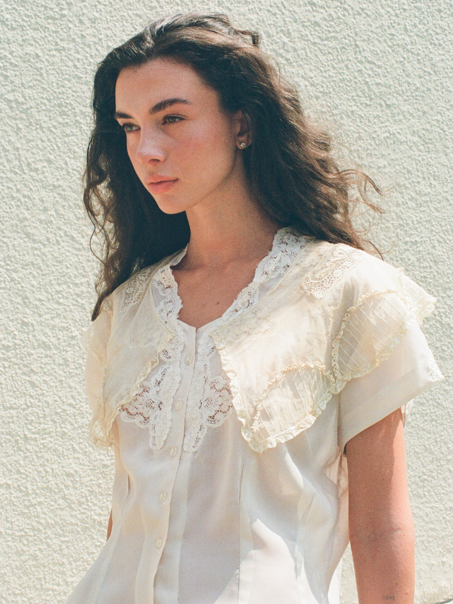Woman wearing a white lace blouse against a light background