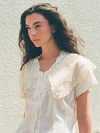 Woman wearing a white lace blouse against a light background