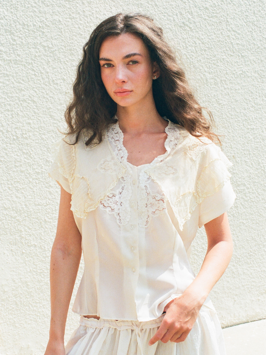 Woman wearing a white lace top against a light background