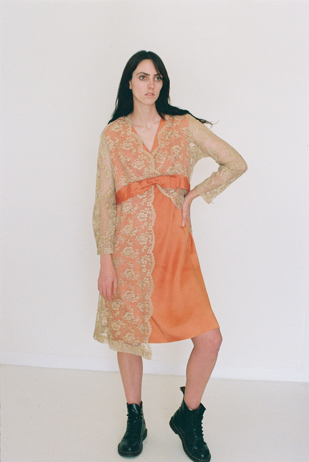 Woman wearing an orange dress with a sheer overlay against a white background