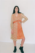 Woman wearing an orange dress with a sheer overlay against a white background