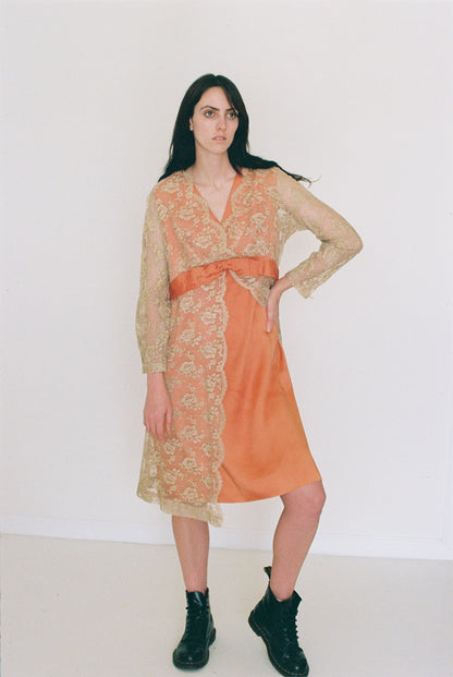 Woman wearing an orange dress with a sheer overlay against a white background