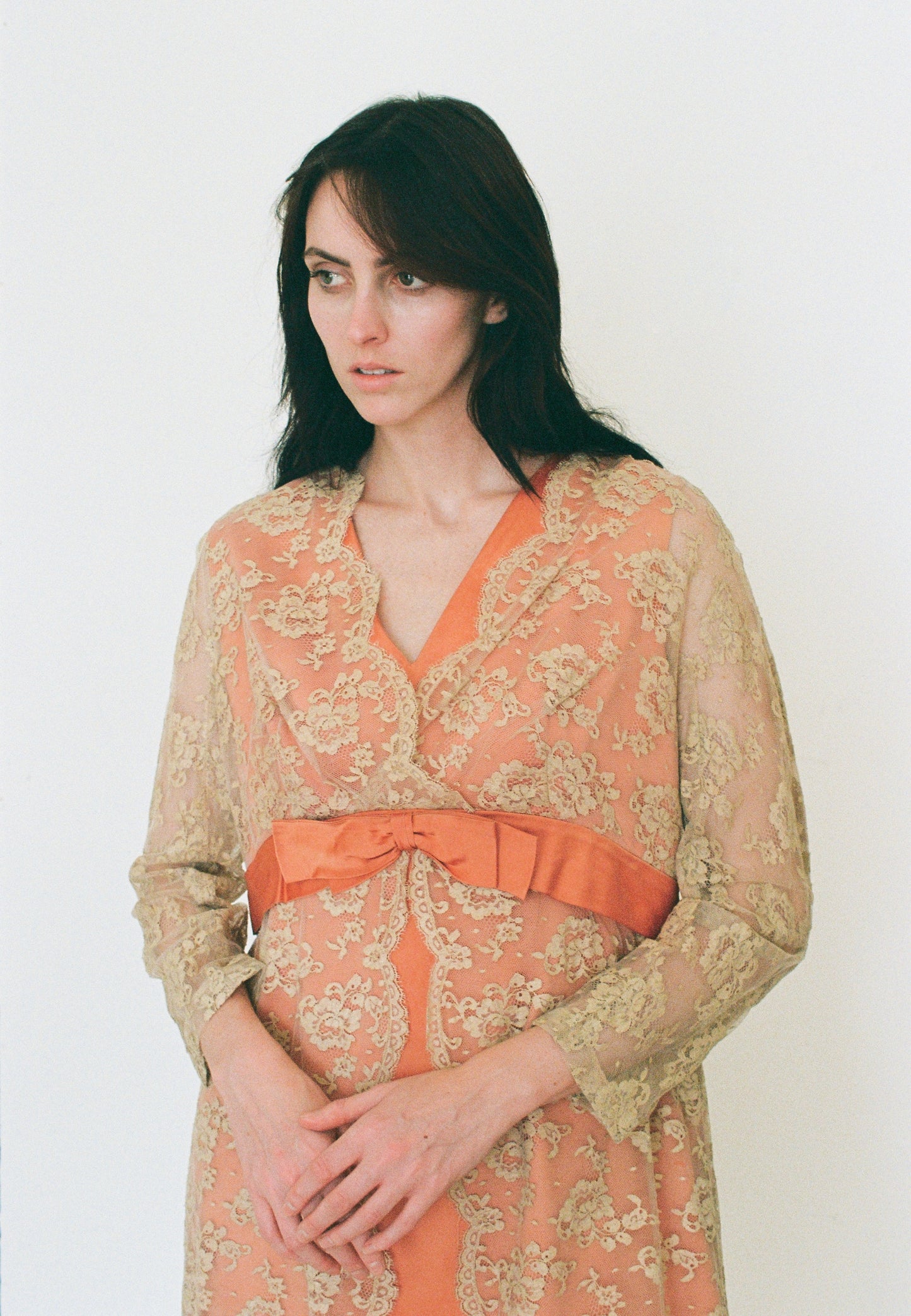 Woman wearing a floral dress with an orange belt against a white background