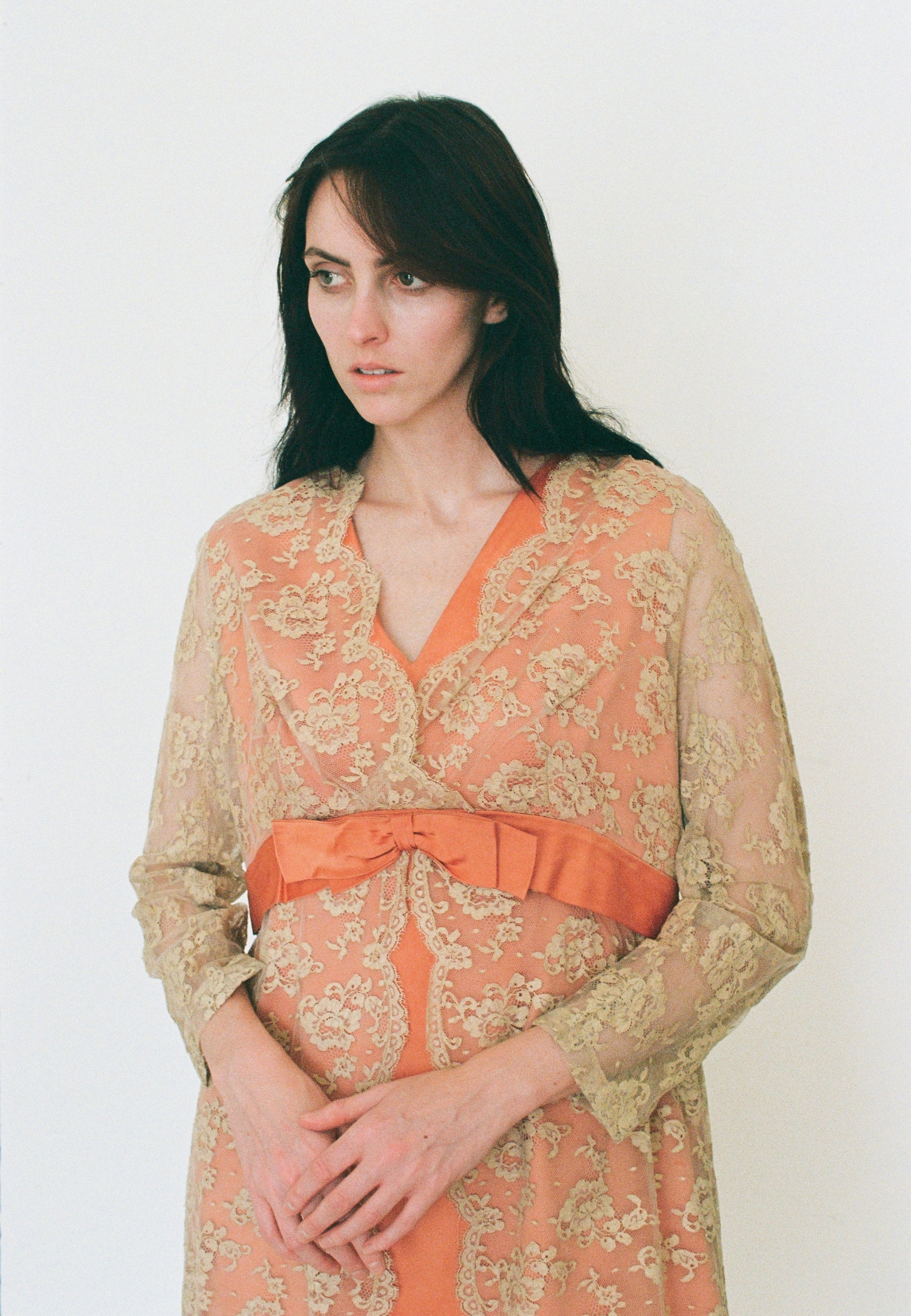 Woman wearing a floral dress with an orange belt against a white background