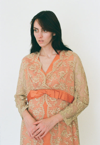 Woman wearing a floral dress with an orange belt against a white background