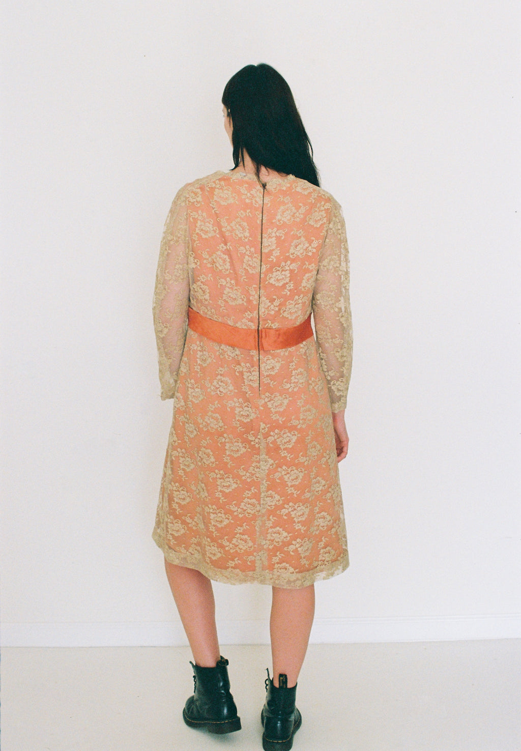 Person wearing a floral dress with a red belt against a white background