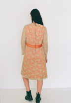 Person wearing a floral dress with a red belt against a white background