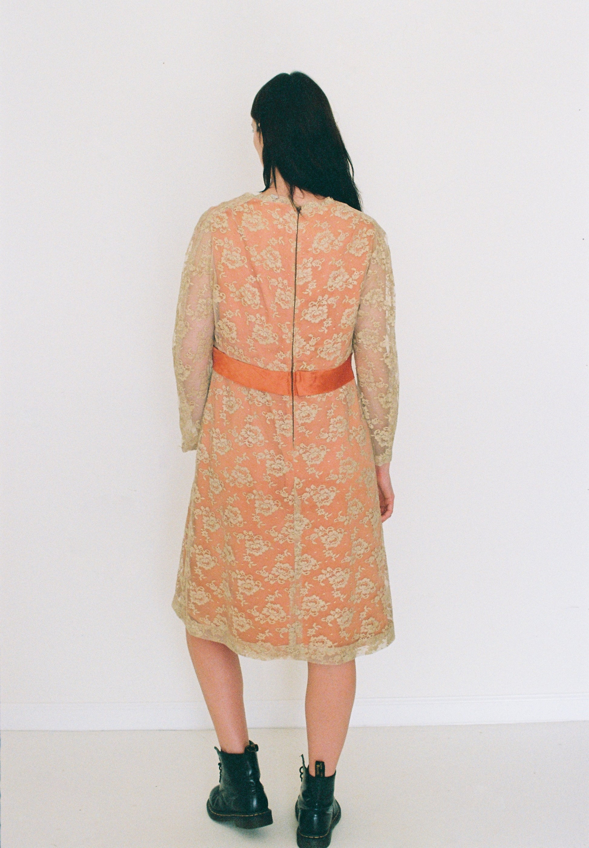 Person wearing a floral dress with a red belt against a white background