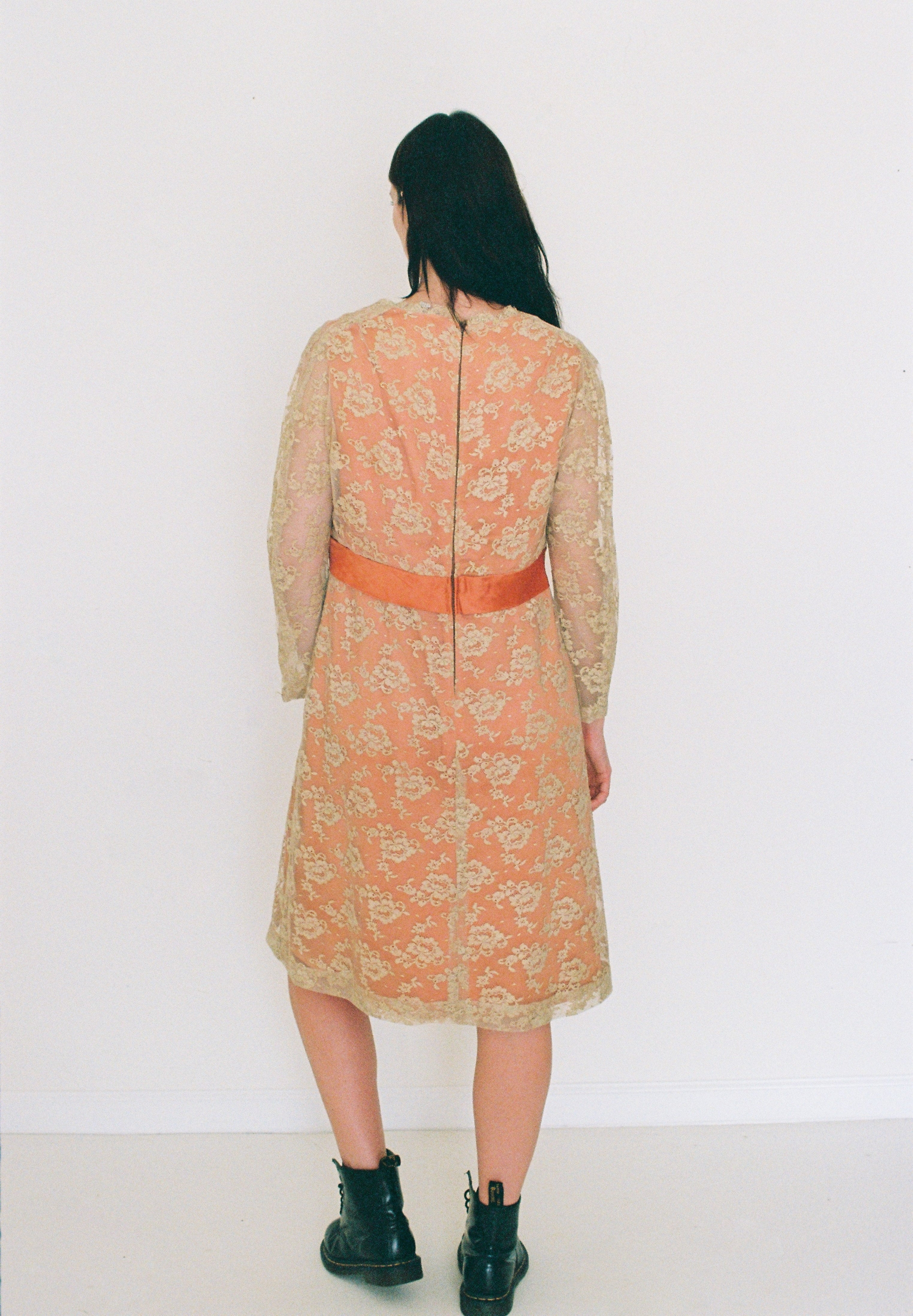 Person wearing a floral dress with a red belt against a white background