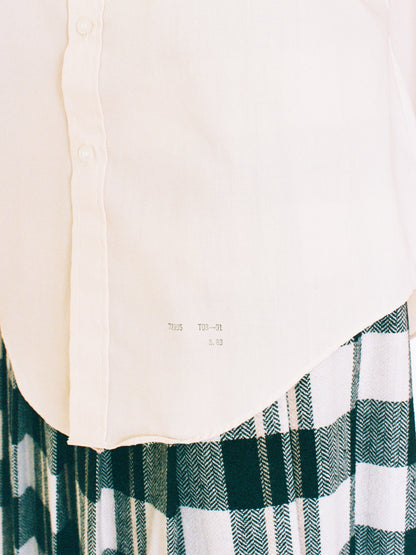 Close-up of a white shirt with a plaid pattern skirt on a plain background