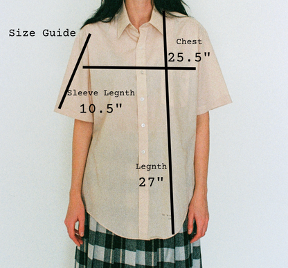 Beige shirt with measurements labeled on a plain background