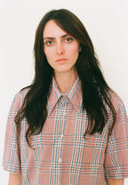 Person wearing a plaid shirt against a plain background