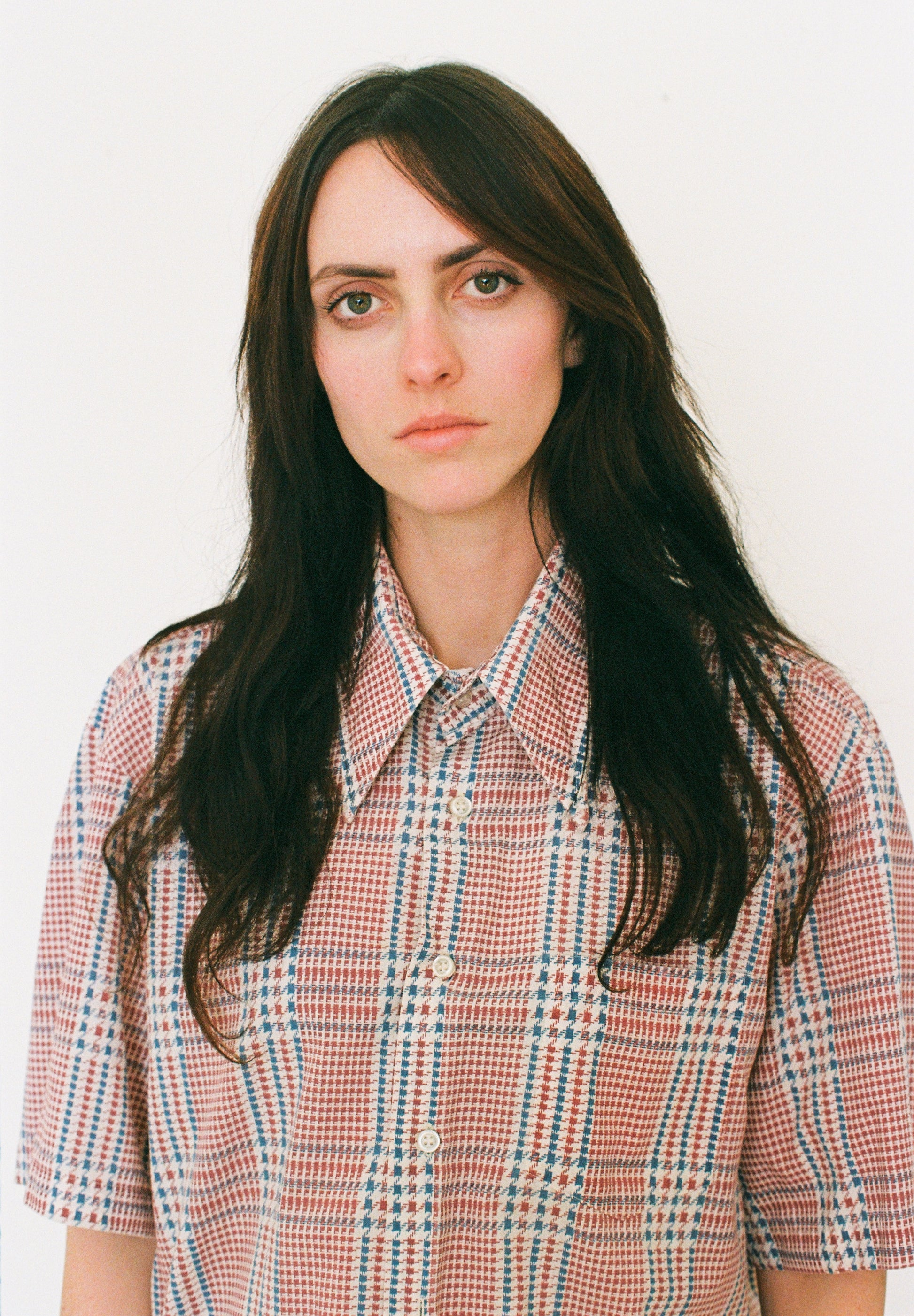Person wearing a plaid shirt against a plain background