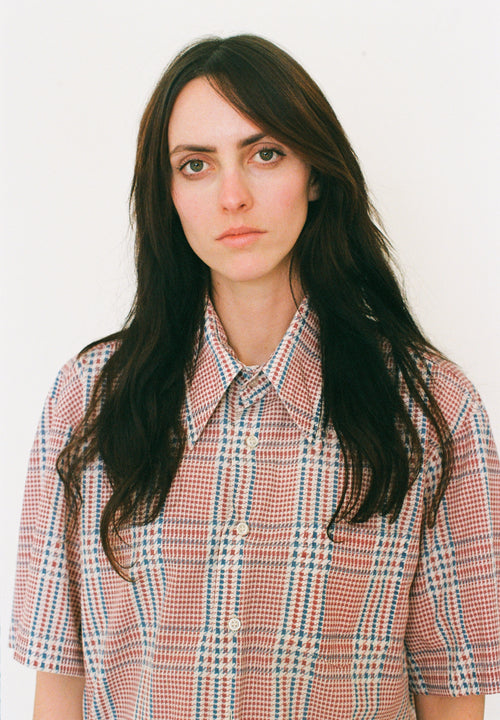 Person wearing a plaid shirt against a plain background