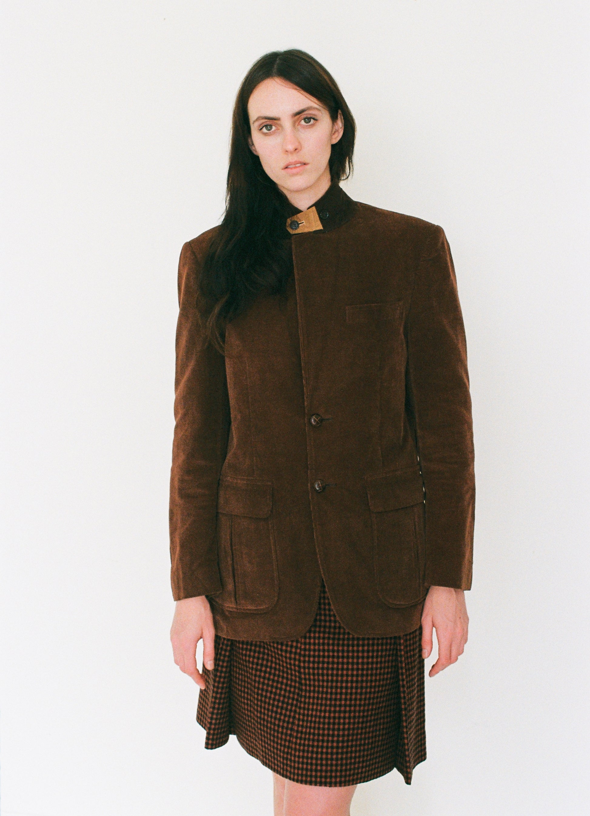 Woman wearing a brown jacket and skirt on a white background