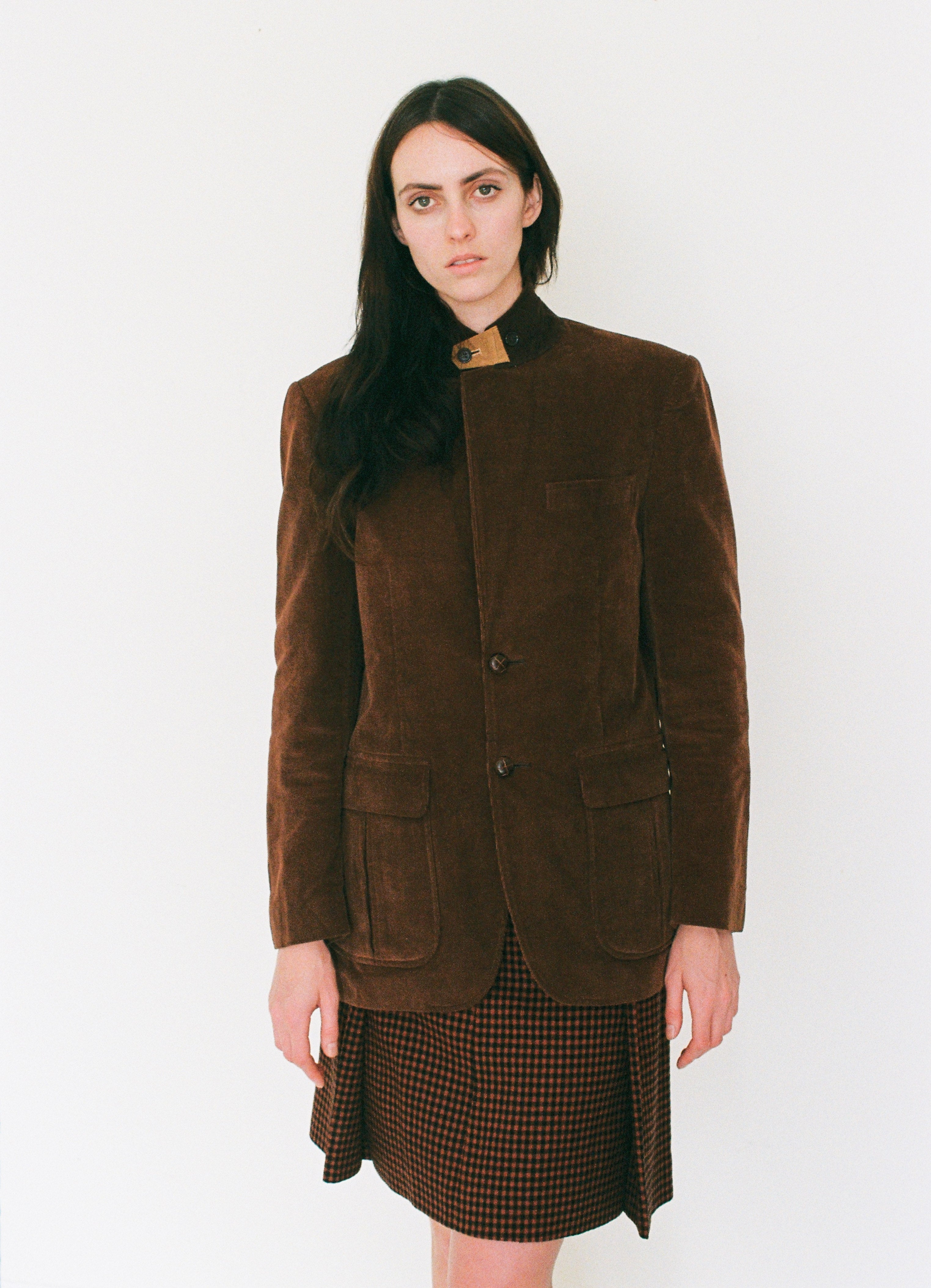 Woman wearing a brown jacket and skirt on a white background