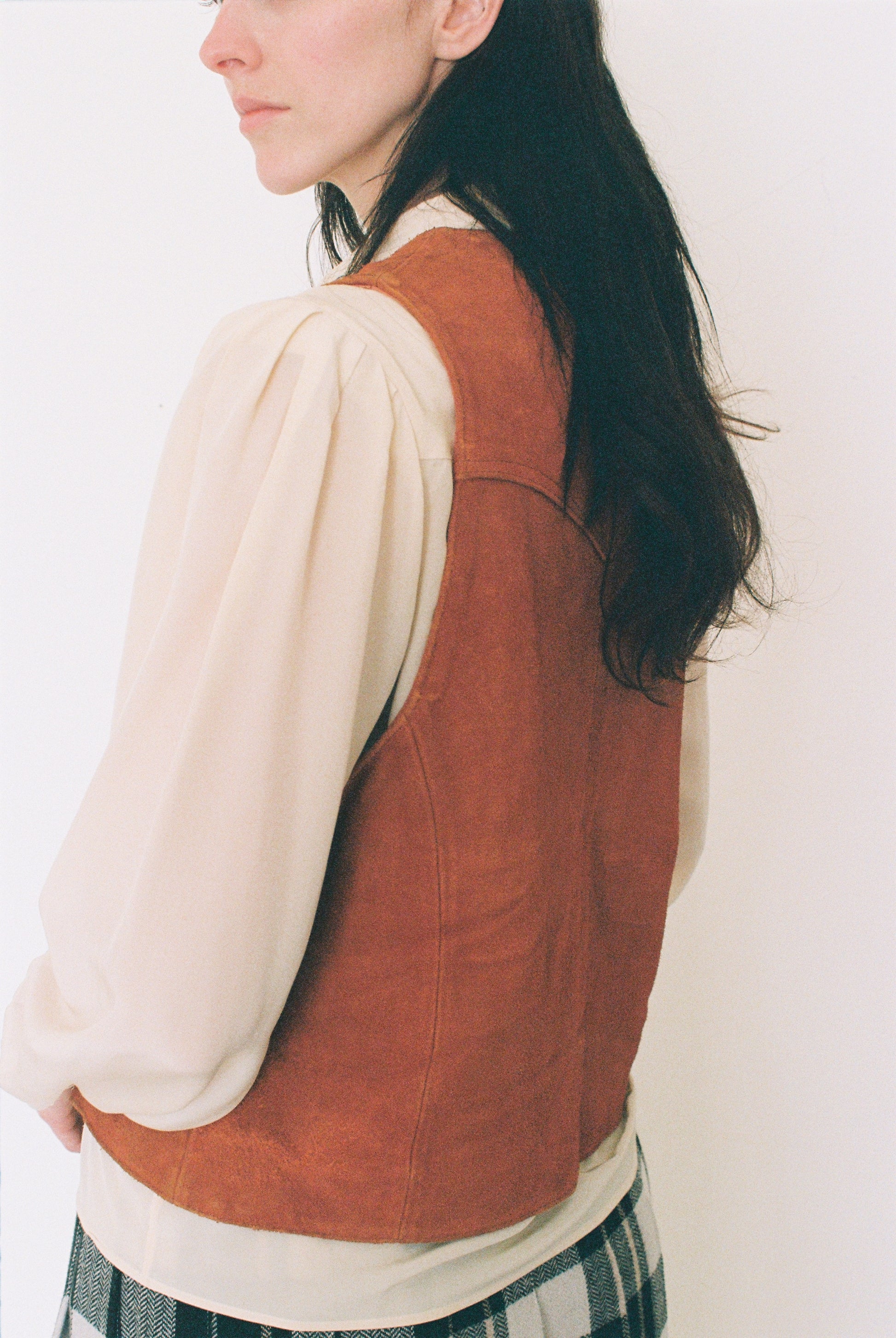 Person wearing a orange vest over a white shirt with a plain background