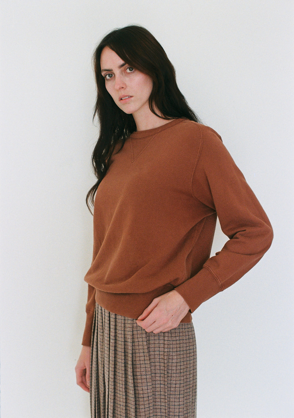 Woman wearing a brown sweater against a white background