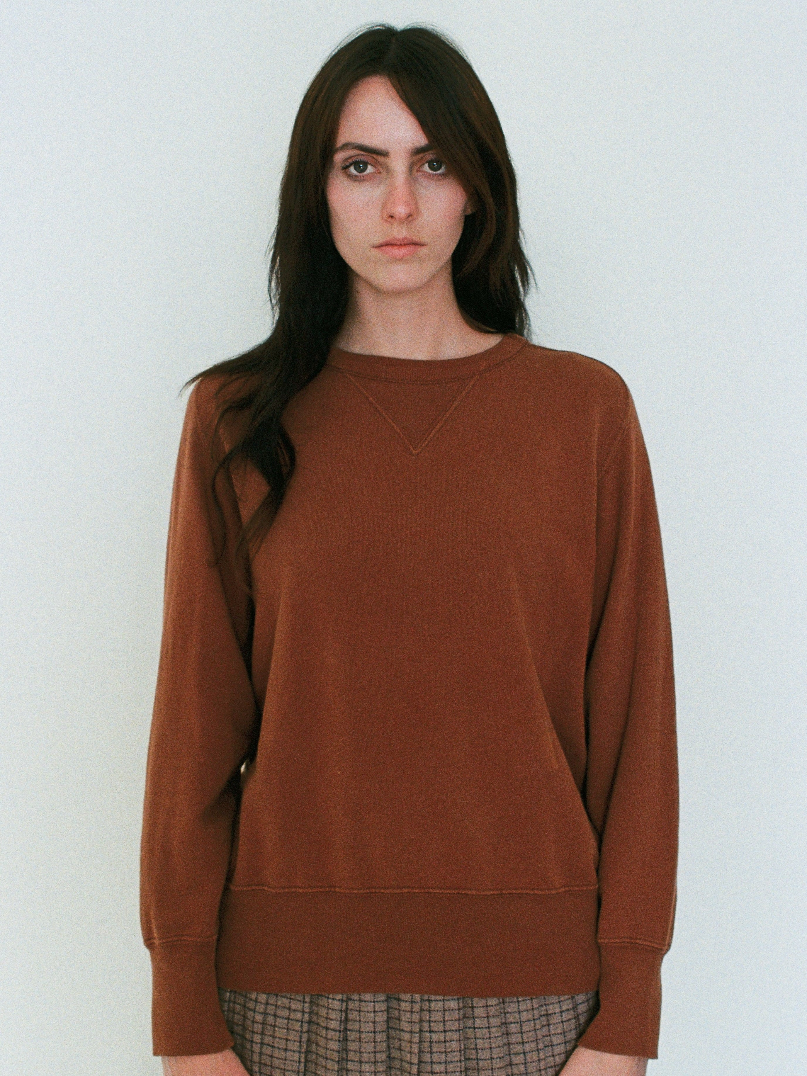 Woman wearing a brown sweatshirt against a white background