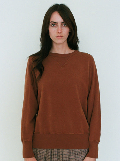 Woman wearing a brown sweatshirt against a white background