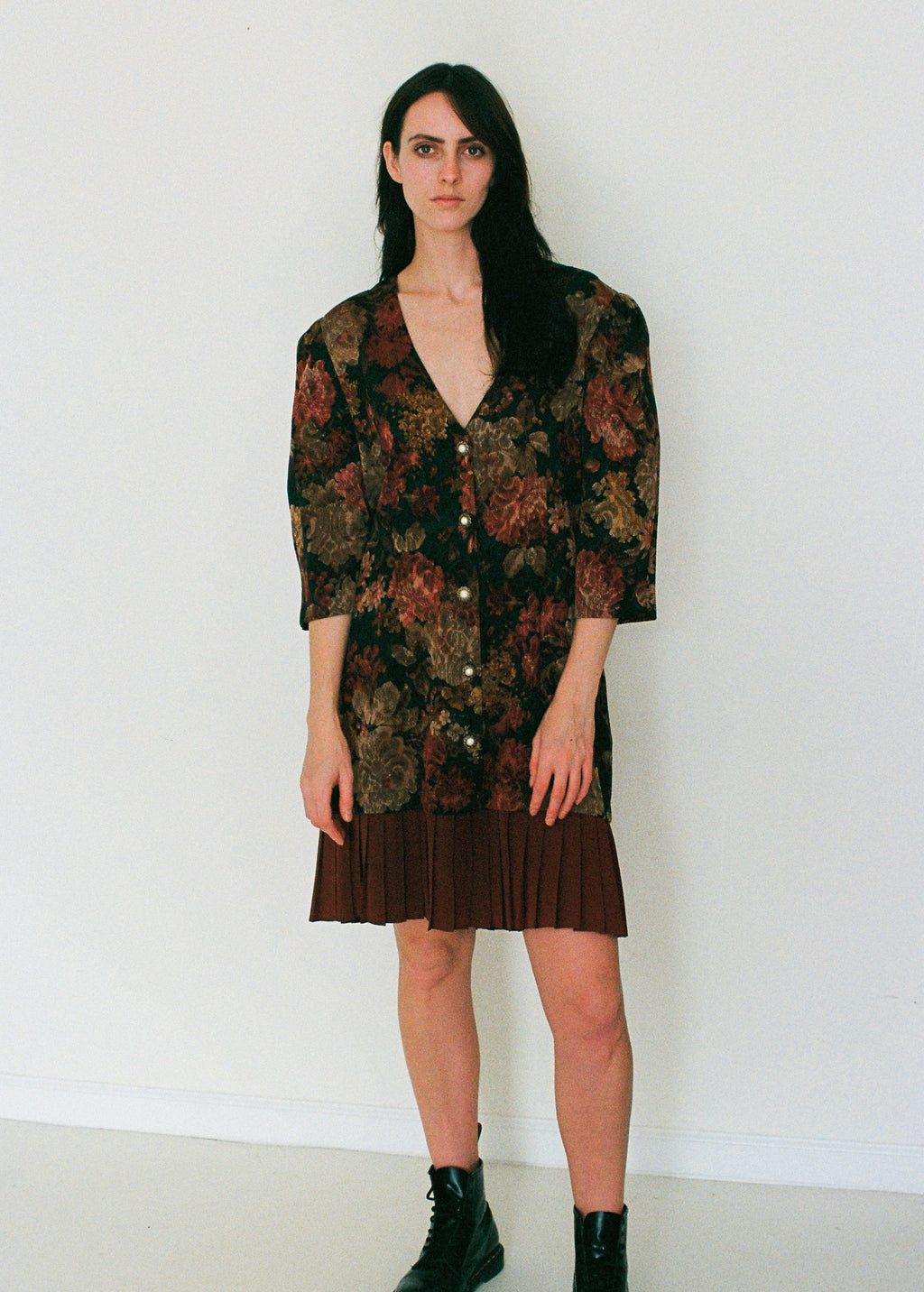Woman wearing a floral patterned pleated dress against a white background