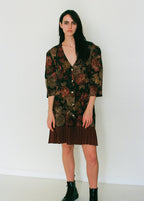 Woman wearing a floral patterned pleated dress against a white background