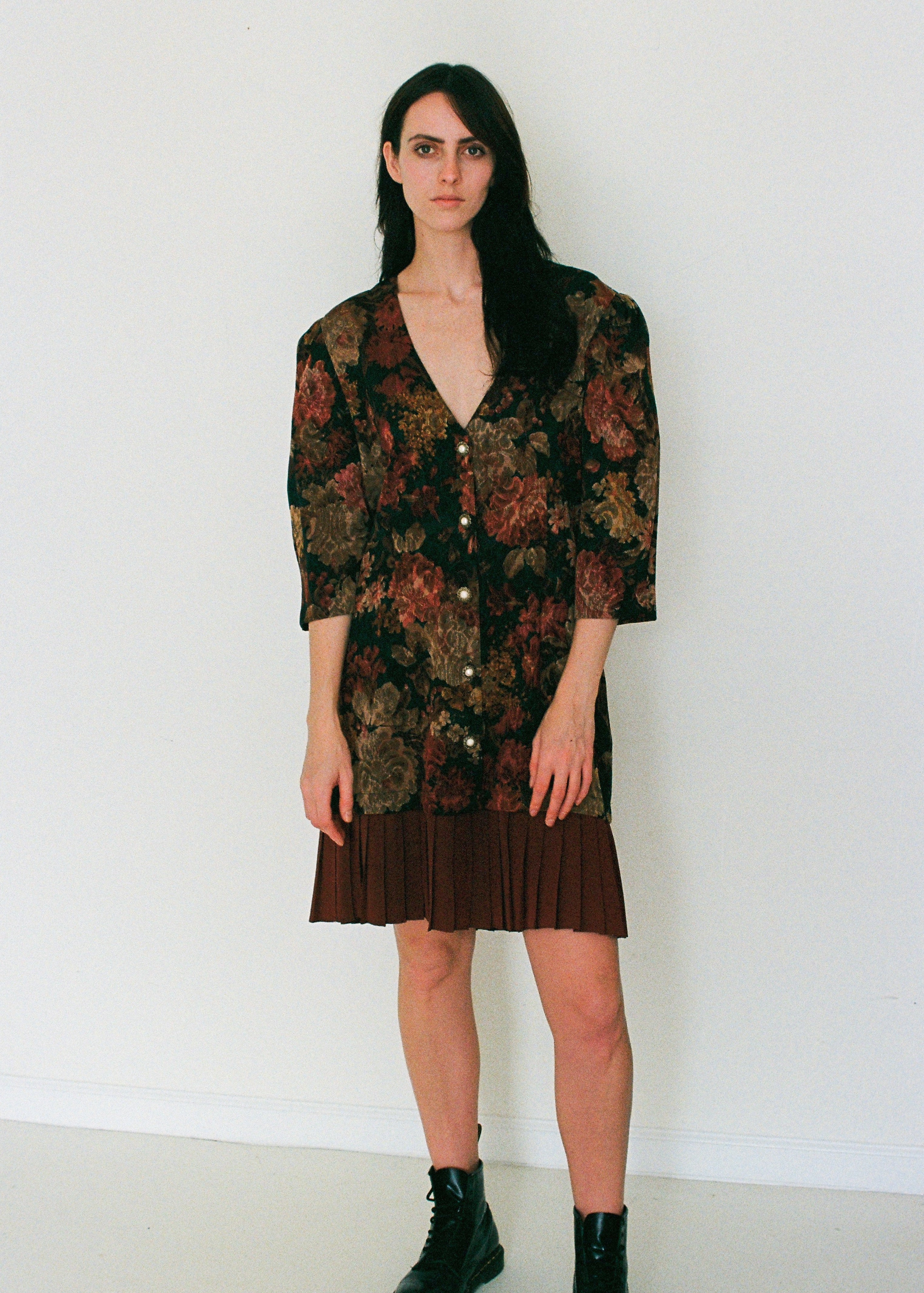 Woman wearing a floral patterned pleated dress against a white background