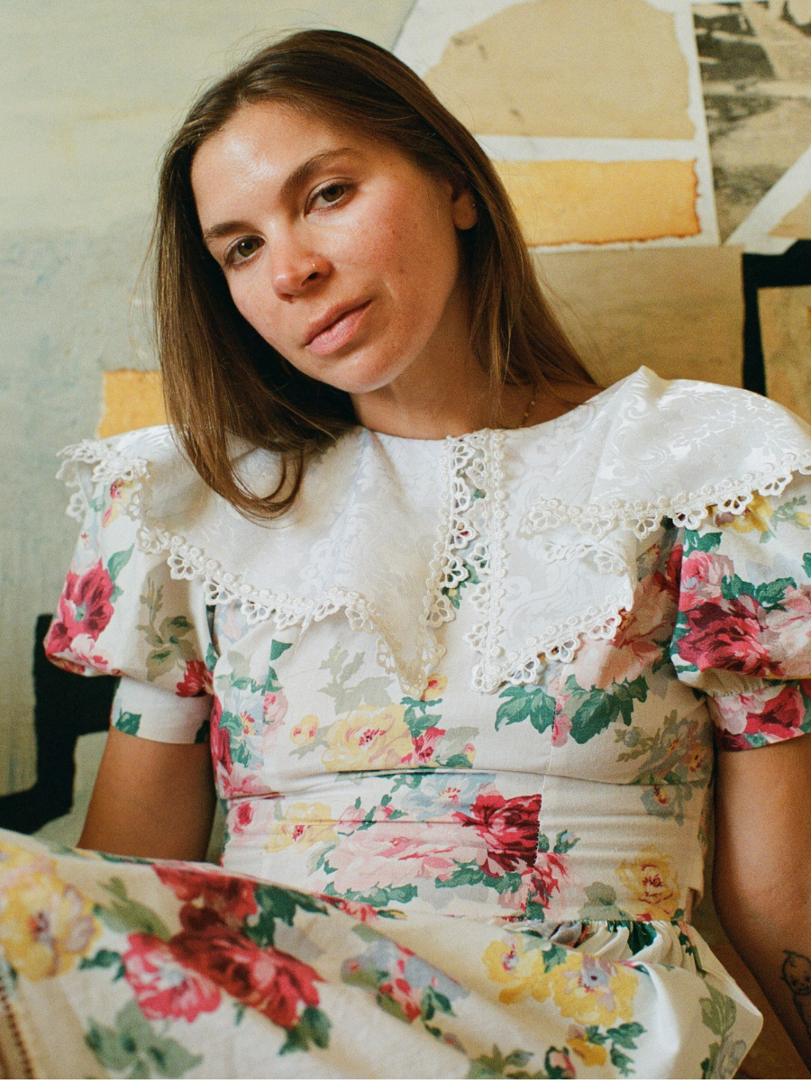 Woman wearing a floral dress sitting on a couch.