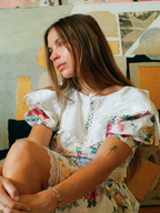 Woman in a floral dress sitting against a colorful abstract wall.
