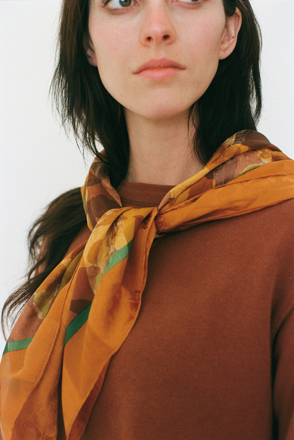 Woman wearing a patterned scarf on a plain background