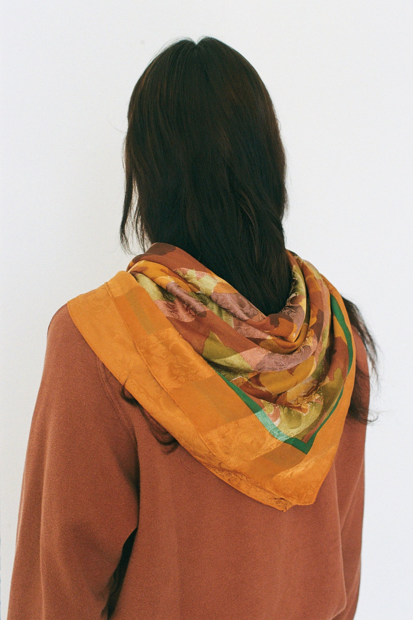 Person wearing a colorful scarf on a plain background