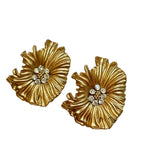 Pair of gold floral earrings with embedded stones on a white background