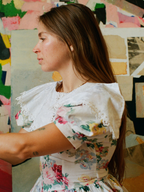 Woman wearing a floral dress with a colorful abstract painting in the background