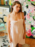 Woman in a light pink dress standing in front of a colorful abstract wall.
