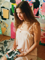 Woman holding a book in front of a colorful abstract wall.