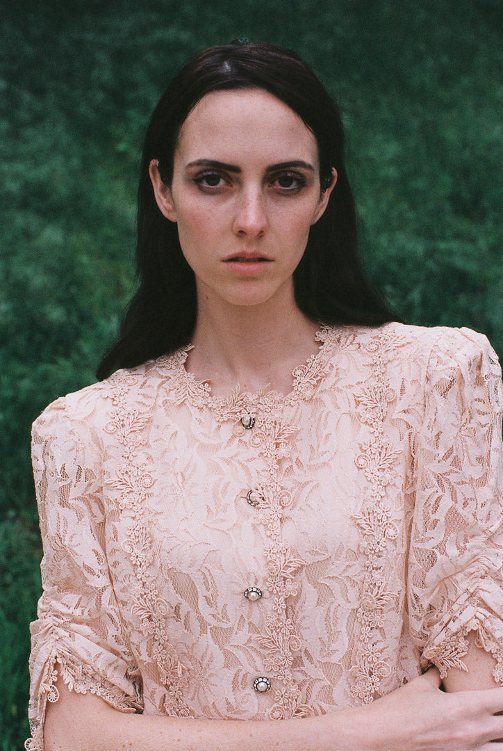 Woman wearing a lace blouse against a green background